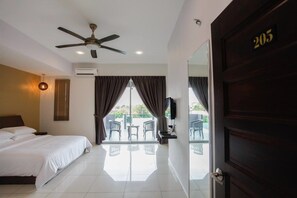 A hotel room with a bed, a ceiling fan, a TV, and a balcony with chairs. - Millenium Maison Home (Alor Setar)