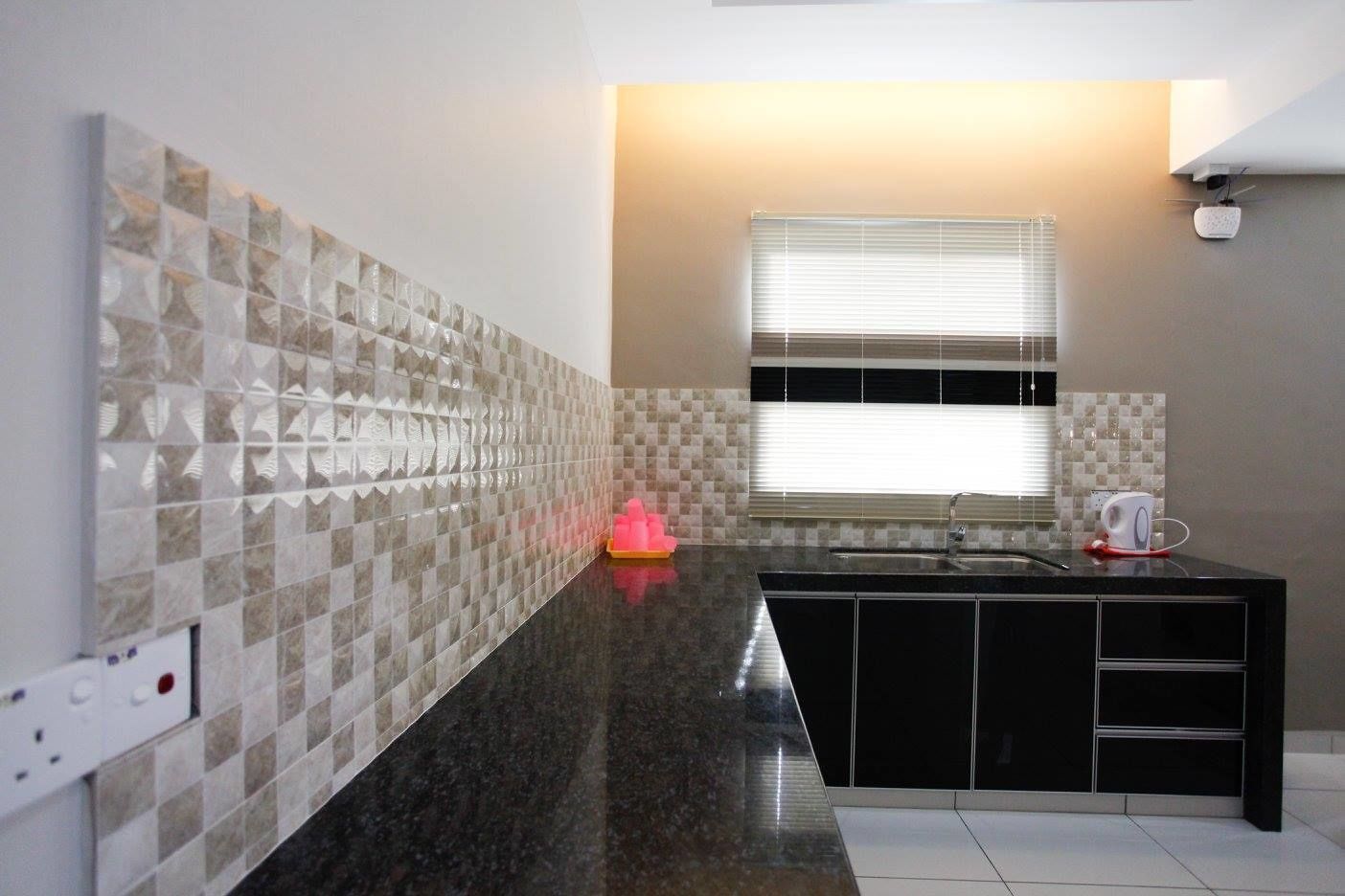A modern kitchen with a black countertop, a window with blinds, and a tiled backsplash.
