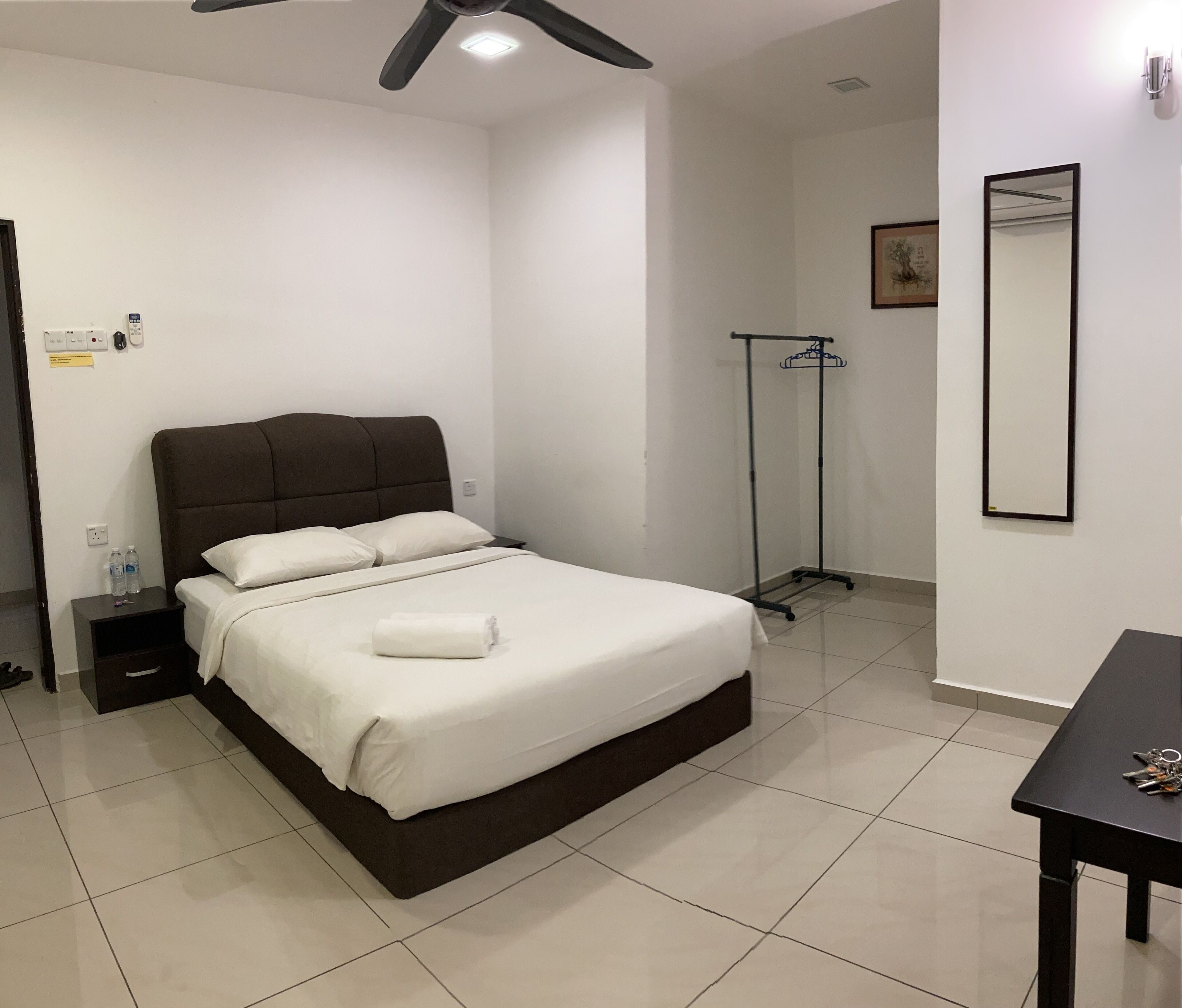 A neatly arranged hotel room with a bed, bedside table, and a small table with keys.