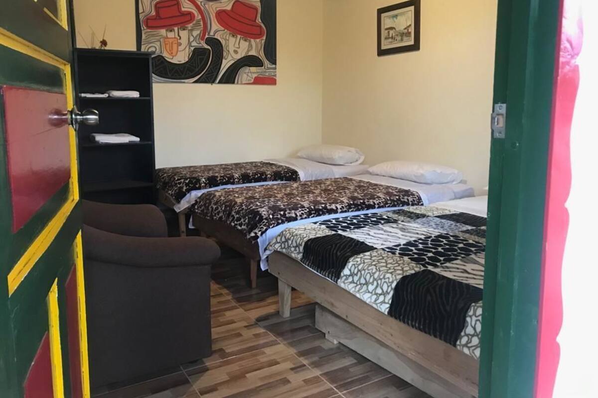 Ett rum med två sängar, en stol, en hylla med handdukar och en tavla på väggen.