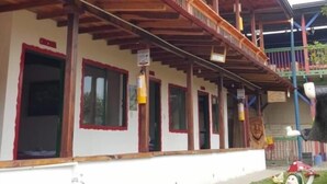 Un edificio con balcón de madera, un letrero que indica un restaurante y una estatua en el jardín delantero.