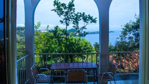 A balcony with a table and chairs, overlooking a scenic view of trees and a body of water. - Rebero Kivu Hotel (Bwishyura)