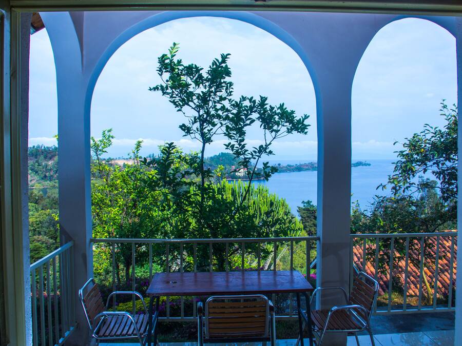A balcony with a table and chairs, overlooking a scenic view of trees and a body of water.