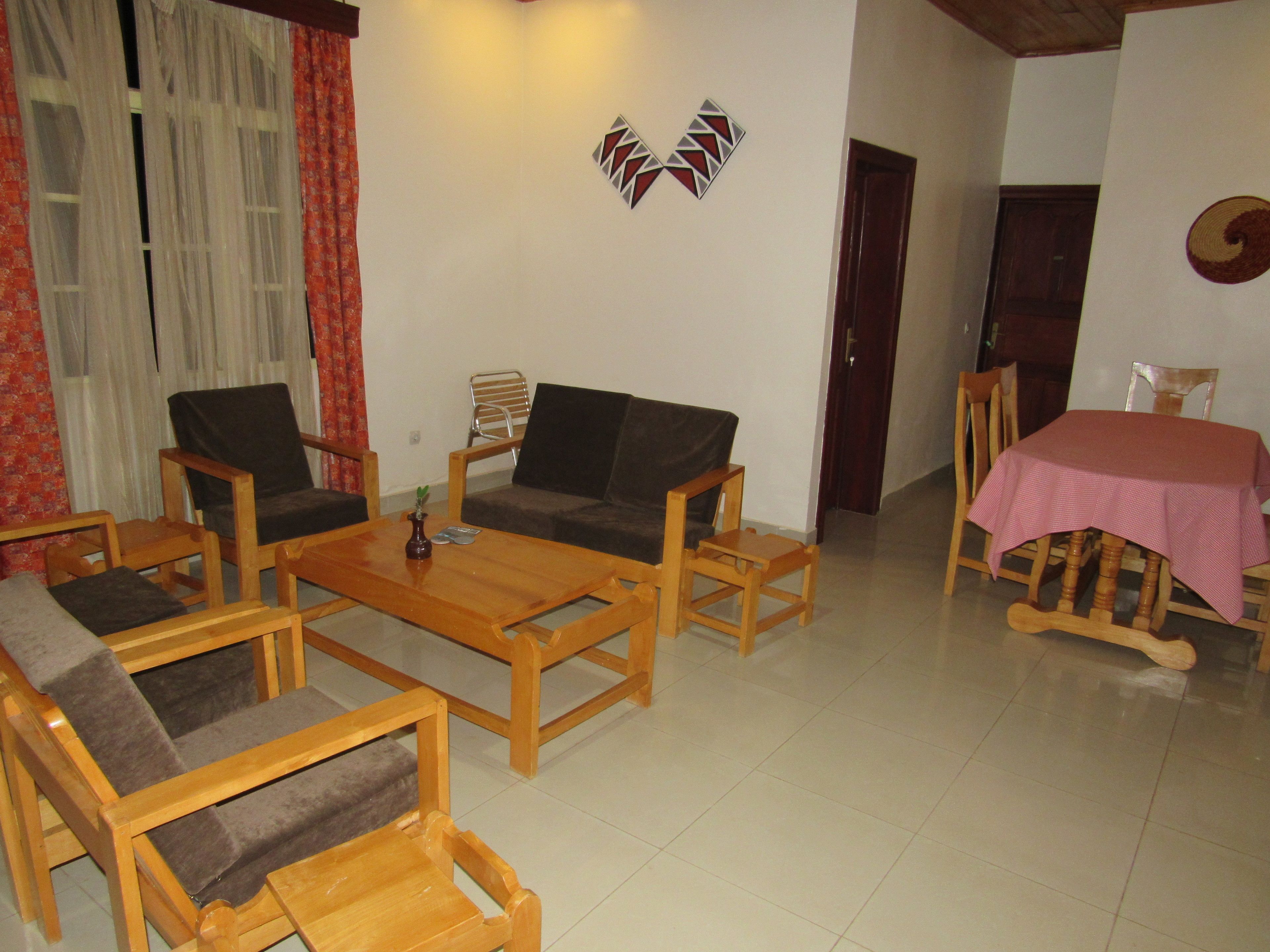 A living room with a wooden coffee table, two sofas, and a dining table with a pink tablecloth.
