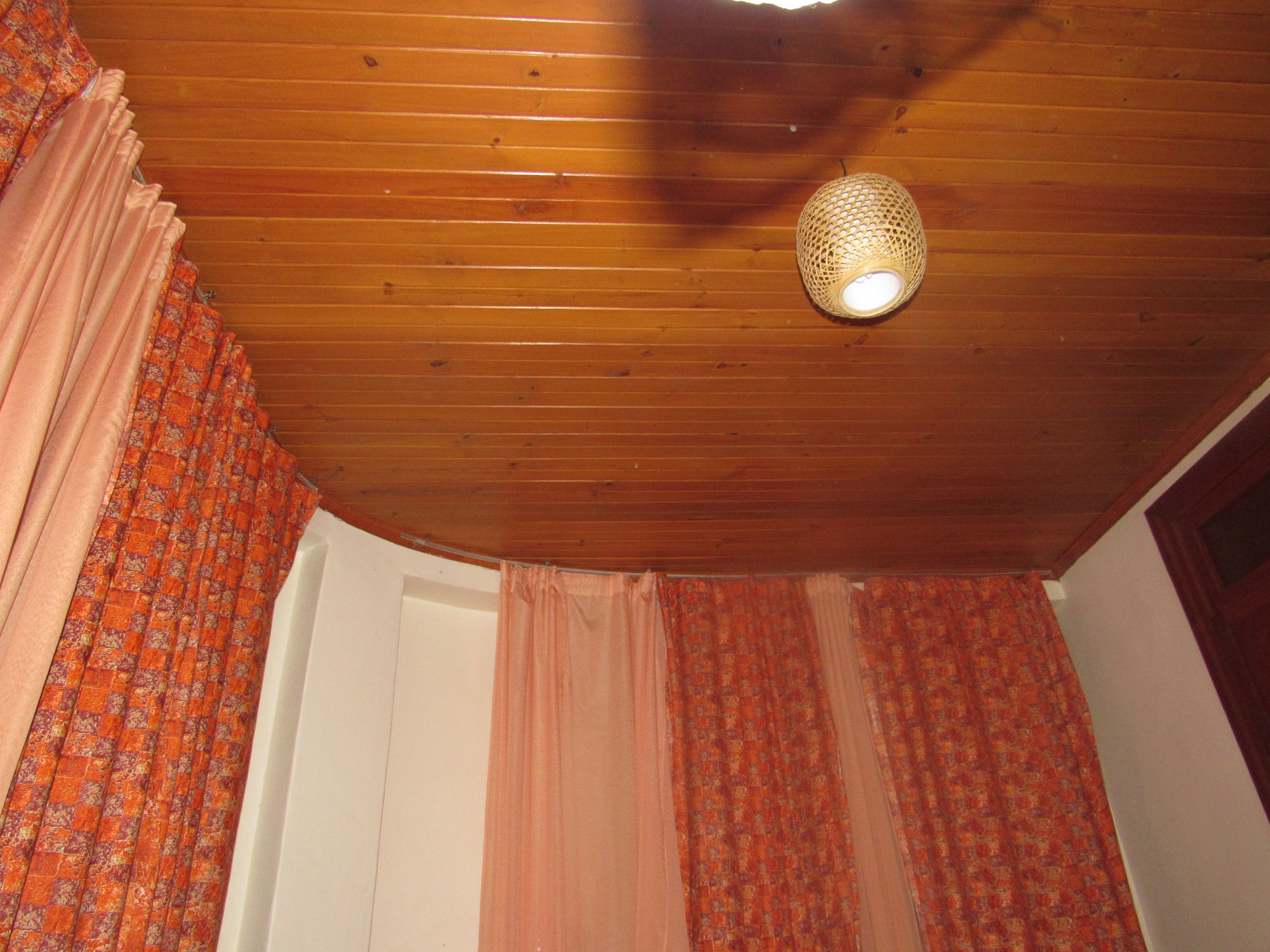 A room with wooden ceiling and patterned curtains.