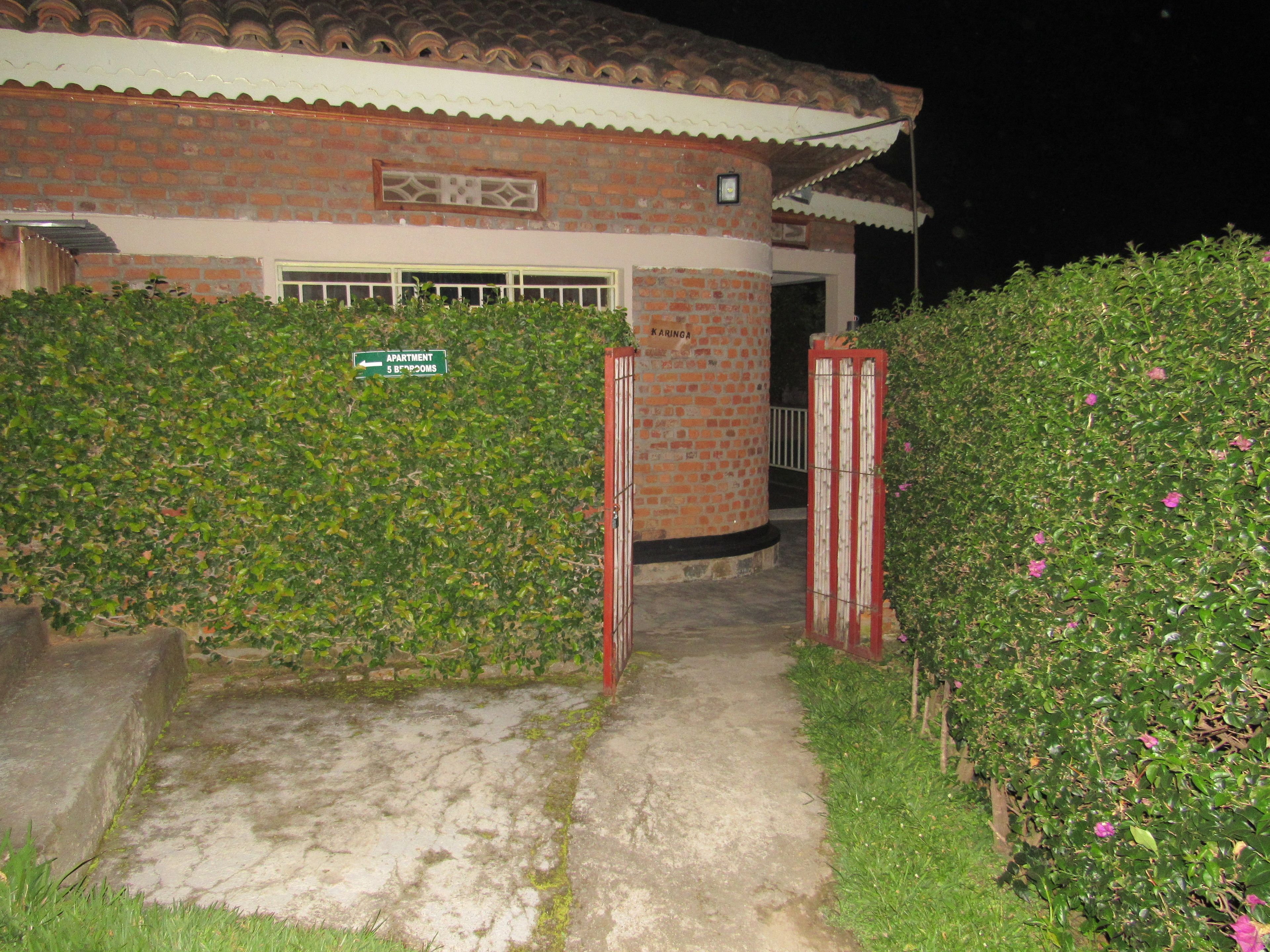 A brick building with a tiled roof, a gated entrance, and a sign indicating an apartment.