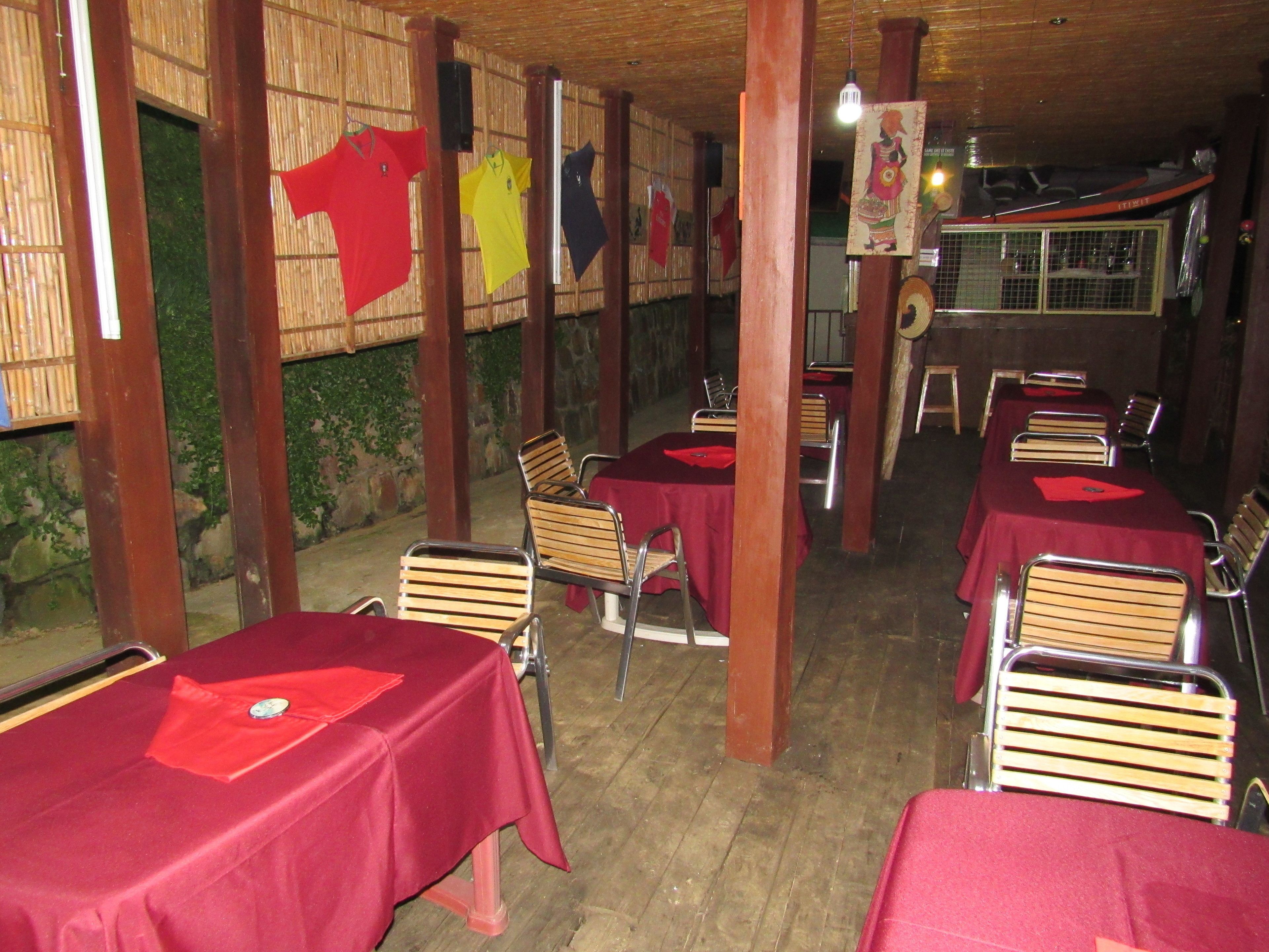 Un restaurante con mesas y sillas de madera, cubiertas con manteles rojos.
