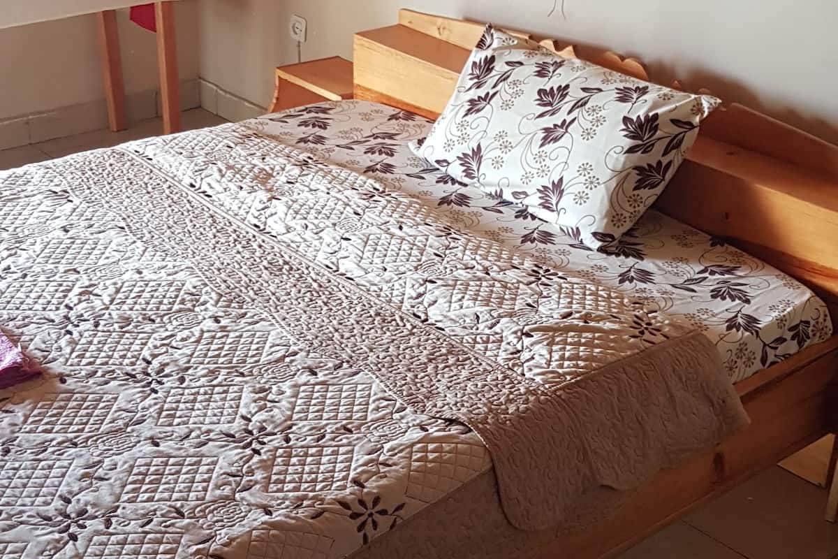 Une chambre à coucher avec un lit, une table de chevet, un baldaquin et une couvre-lit à motifs.