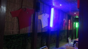 A room with a bamboo wall, a white shirt hanging, and a table with chairs. - Rebero Kivu Hotel (Bwishyura)