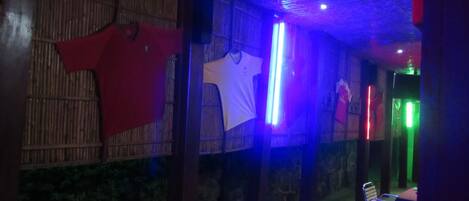 A room with a bamboo wall, a white shirt hanging, and a table with chairs.