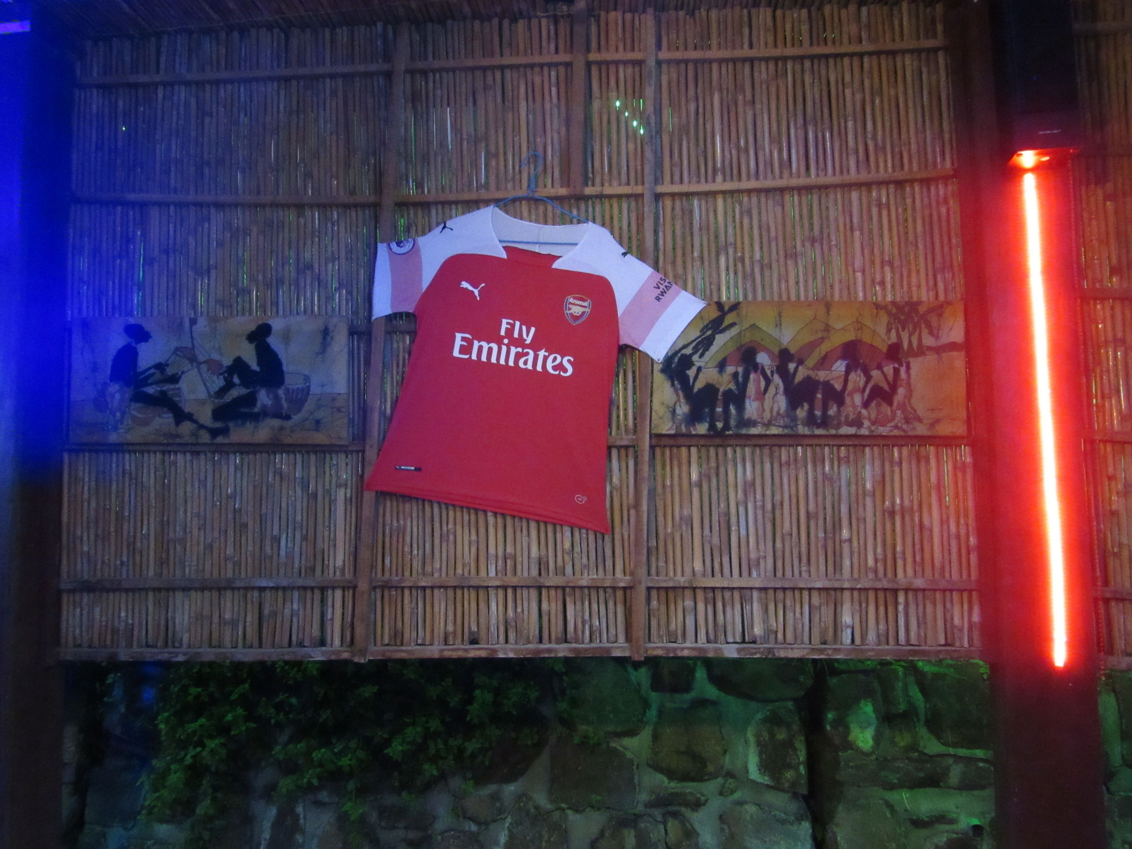 A wall with a red 'Fly Emirates' jersey hanging on it.