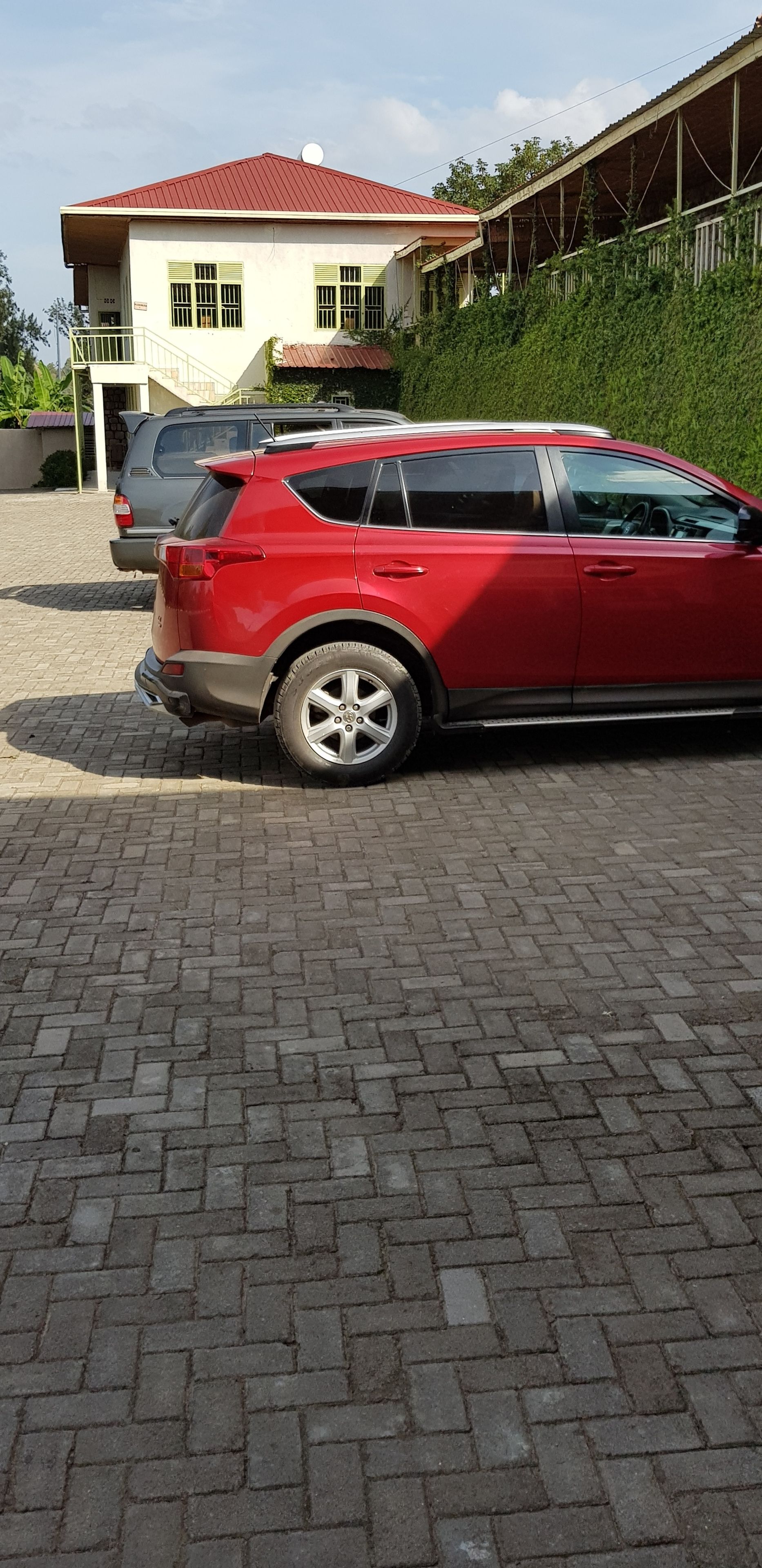 Un SUV rojo estacionado en un camino de entrada pavimentado, con una casa al fondo.