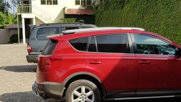 Un SUV rojo estacionado en un camino de entrada pavimentado, con una casa al fondo.