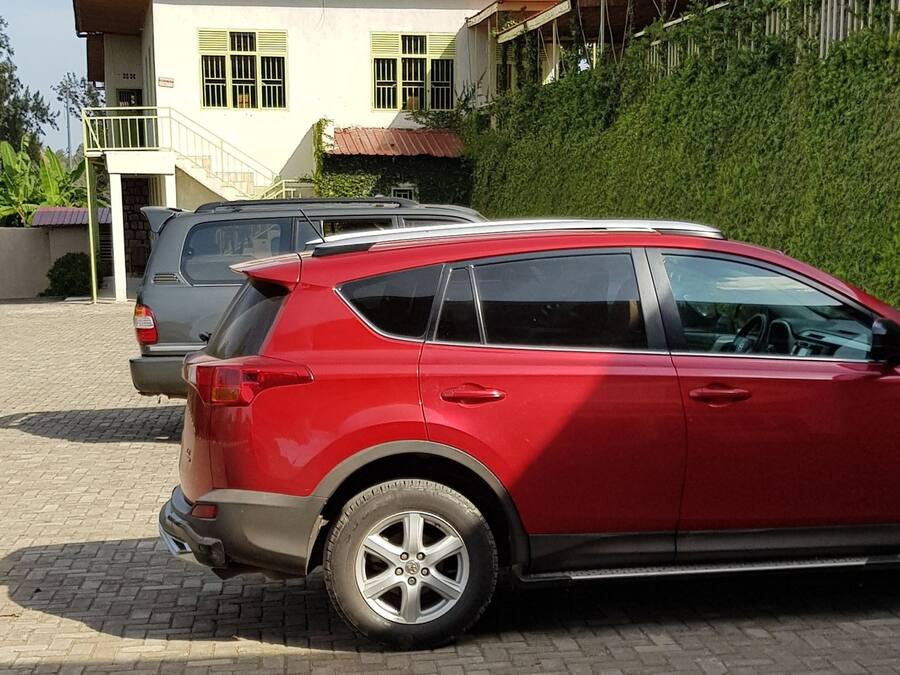 Un SUV rojo estacionado en un camino de entrada pavimentado, con una casa al fondo.