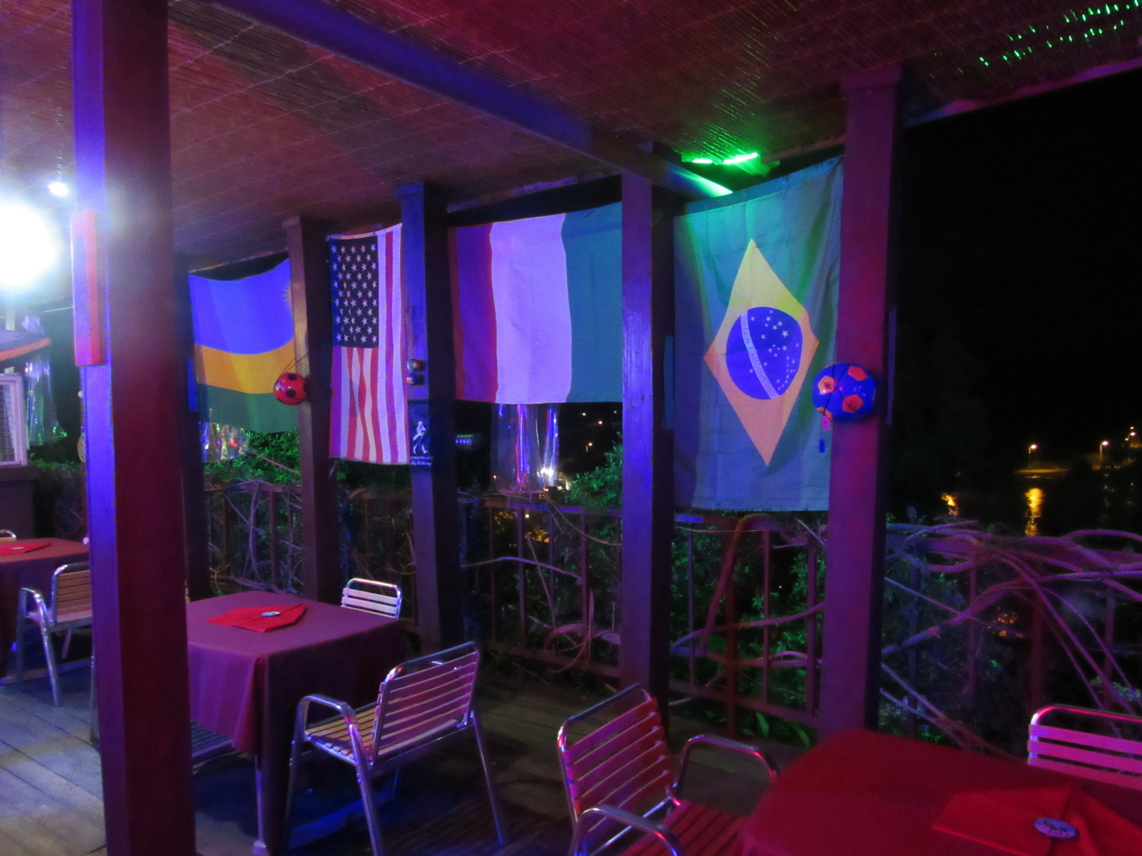 An outdoor dining area with tables and chairs, flags, and a view of the cityscape.