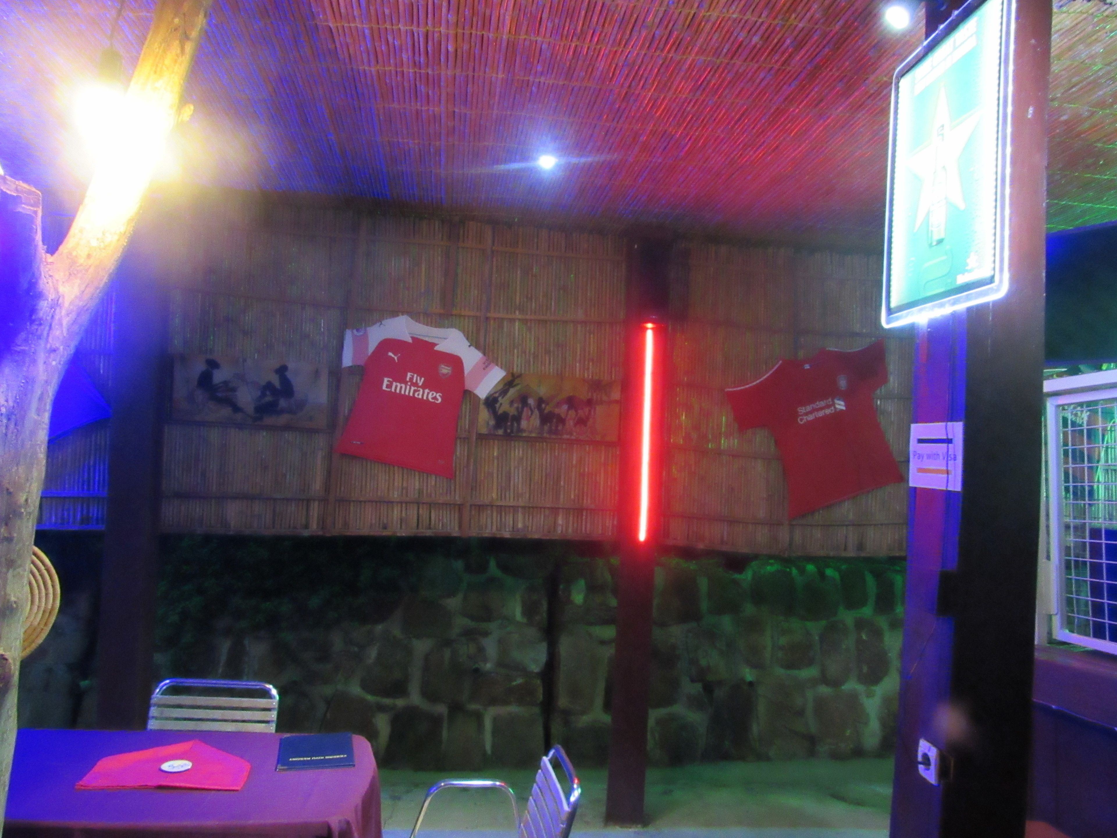 Una habitación con pared de piedra, una mesa cubierta con mantel rojo y una silla roja.