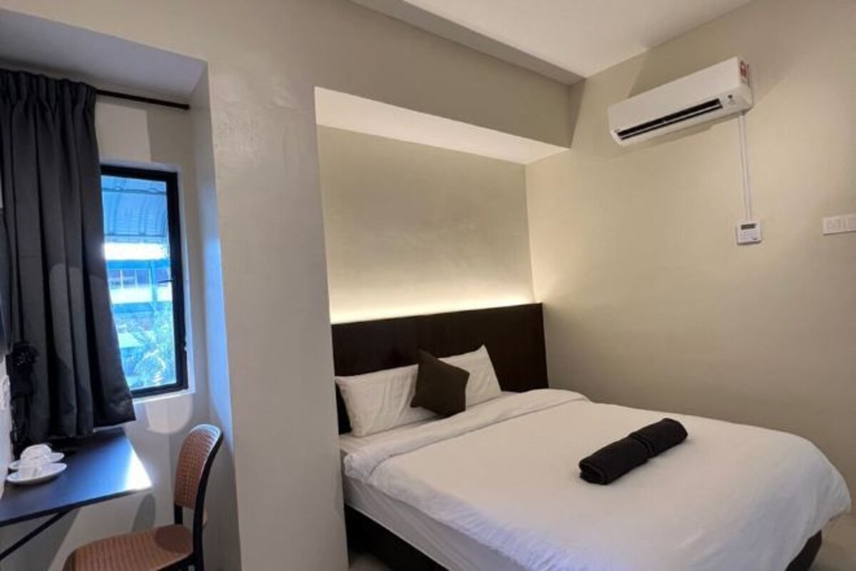 Una habitación de hotel con una cama, un escritorio, una silla y una ventana con cortinas.