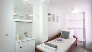 Een nette, kleine kamer met een bed, nachtkastje, spiegel en raam.