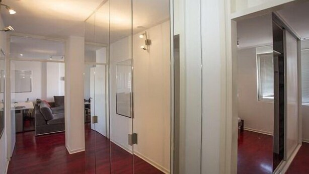 A modern interior with a glass partition, a grey sofa, and a wooden floor. - Apartment Sunset (Belgrade)