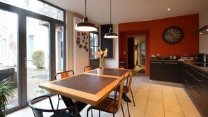 Une cuisine moderne dotée d’un grand îlot central, d’un coin repas avec une table et des chaises en bois, et d’une grande fenêtre offrant une vue sur l’extérieur.