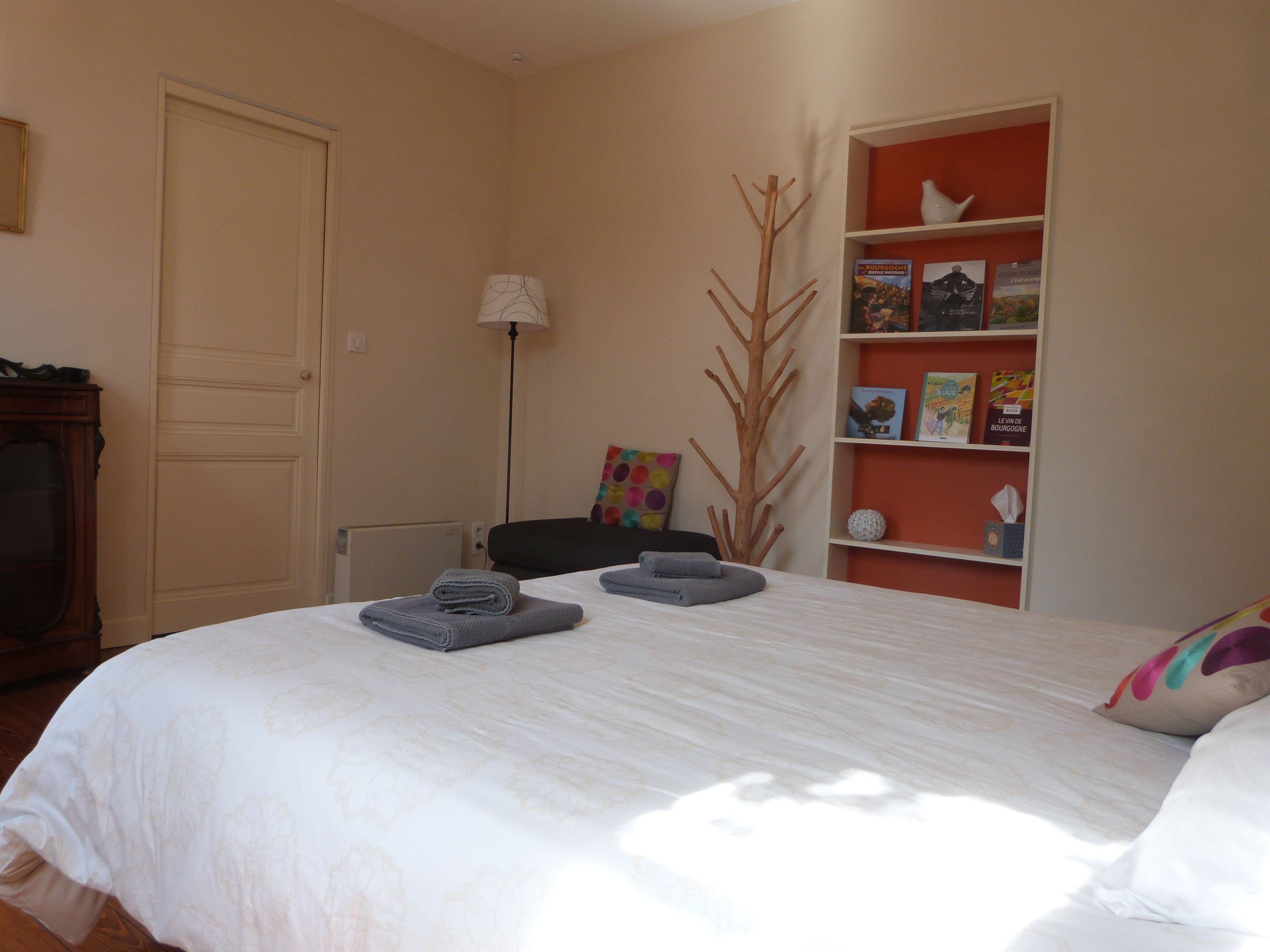 Un dormitorio con una cama, una estantería, una silla y una lámpara.