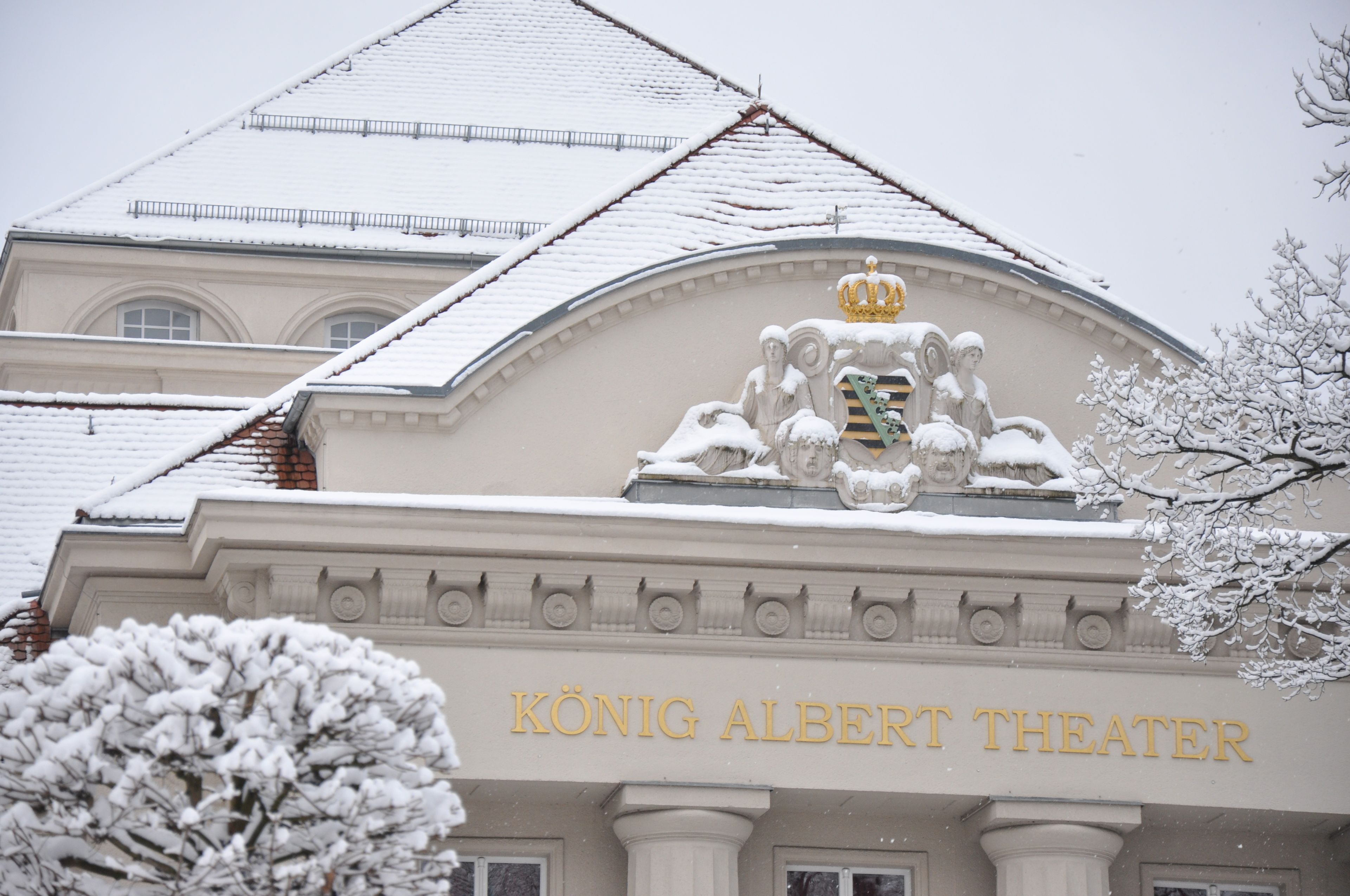 A König Albert Színház homlokzata, hóval borított tetővel és a bejárat felett kiemelkedő koronás emblémával.