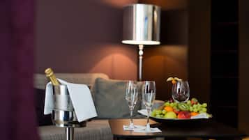 Una mesa con una botella de champán, dos copas y una bandeja de frutas.