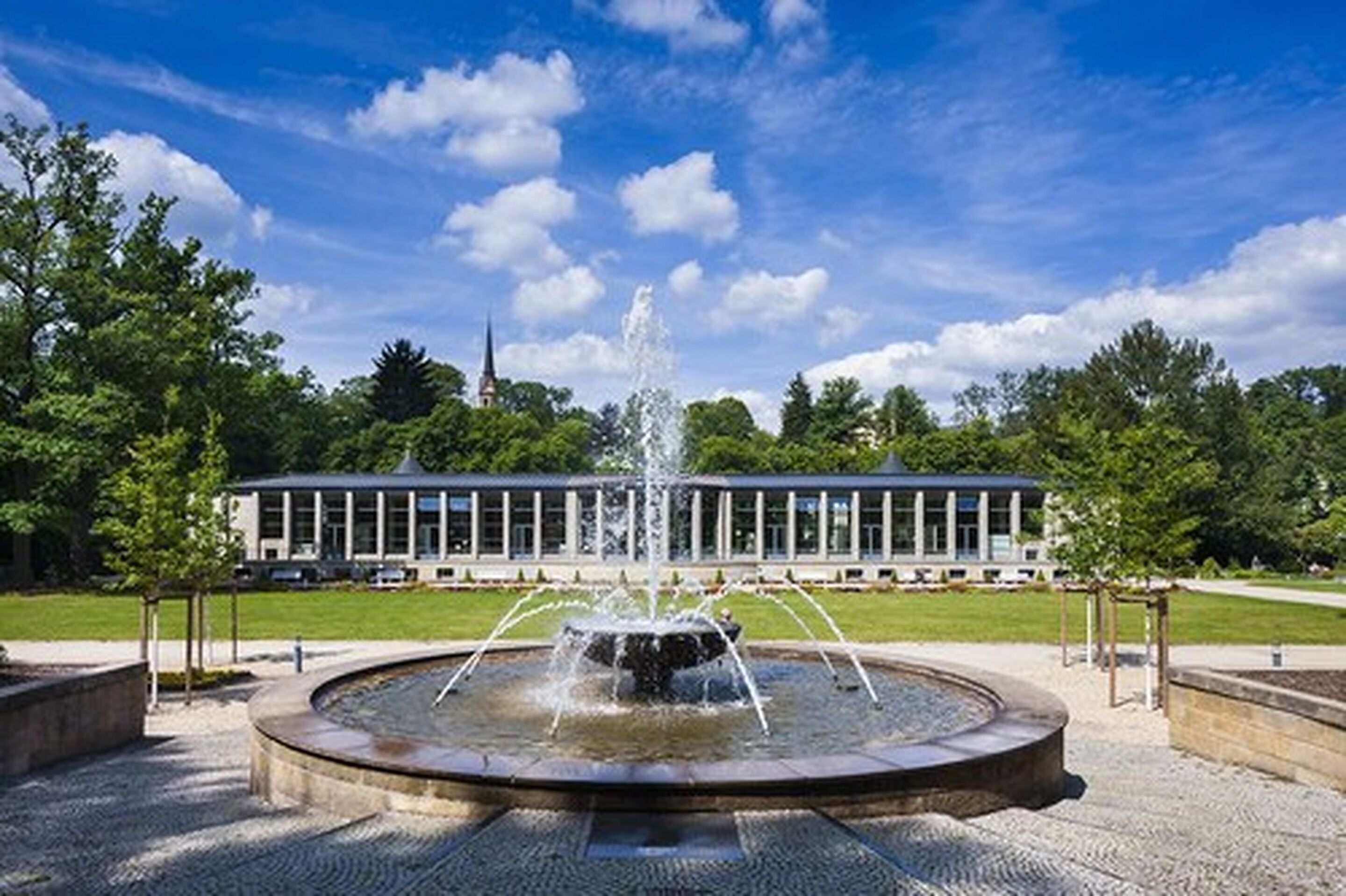 A fountain in a circular basin with a building in the background.