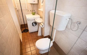 A compact bathroom with a toilet, sink, and washing machine.