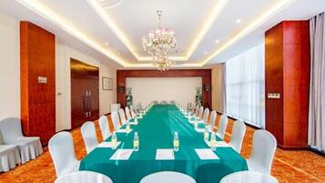 A conference room with a long table, white chairs, and a chandelier.
