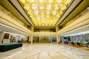 A spacious lobby with a high ceiling and a central circular design on the floor.