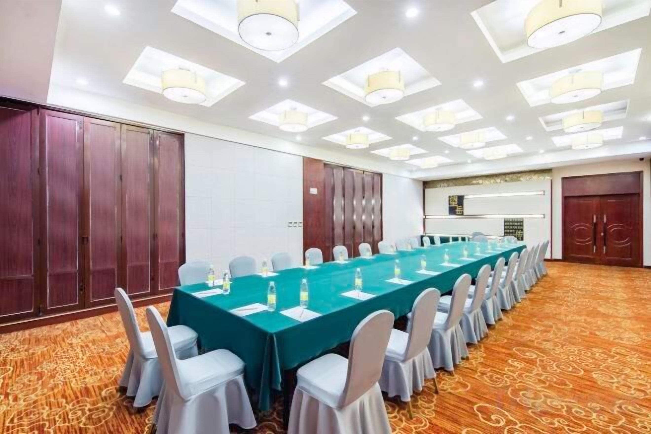 Un salón de conferencias con una mesa larga, sillas y suelo alfombrado.
