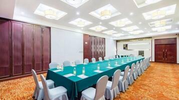 Un salón de conferencias con una mesa larga, sillas y suelo alfombrado.