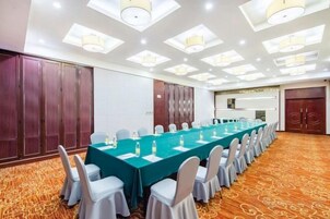 A conference room with a long table, chairs, and a carpeted floor.
