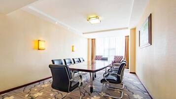 A conference room with a long table, chairs, and a carpeted floor.