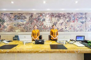 Two individuals seated at a long table with laptops, a microphone, and a speaker, with a large artwork on the wall behind them. - Taishan Royal Hotel (Tai'an)