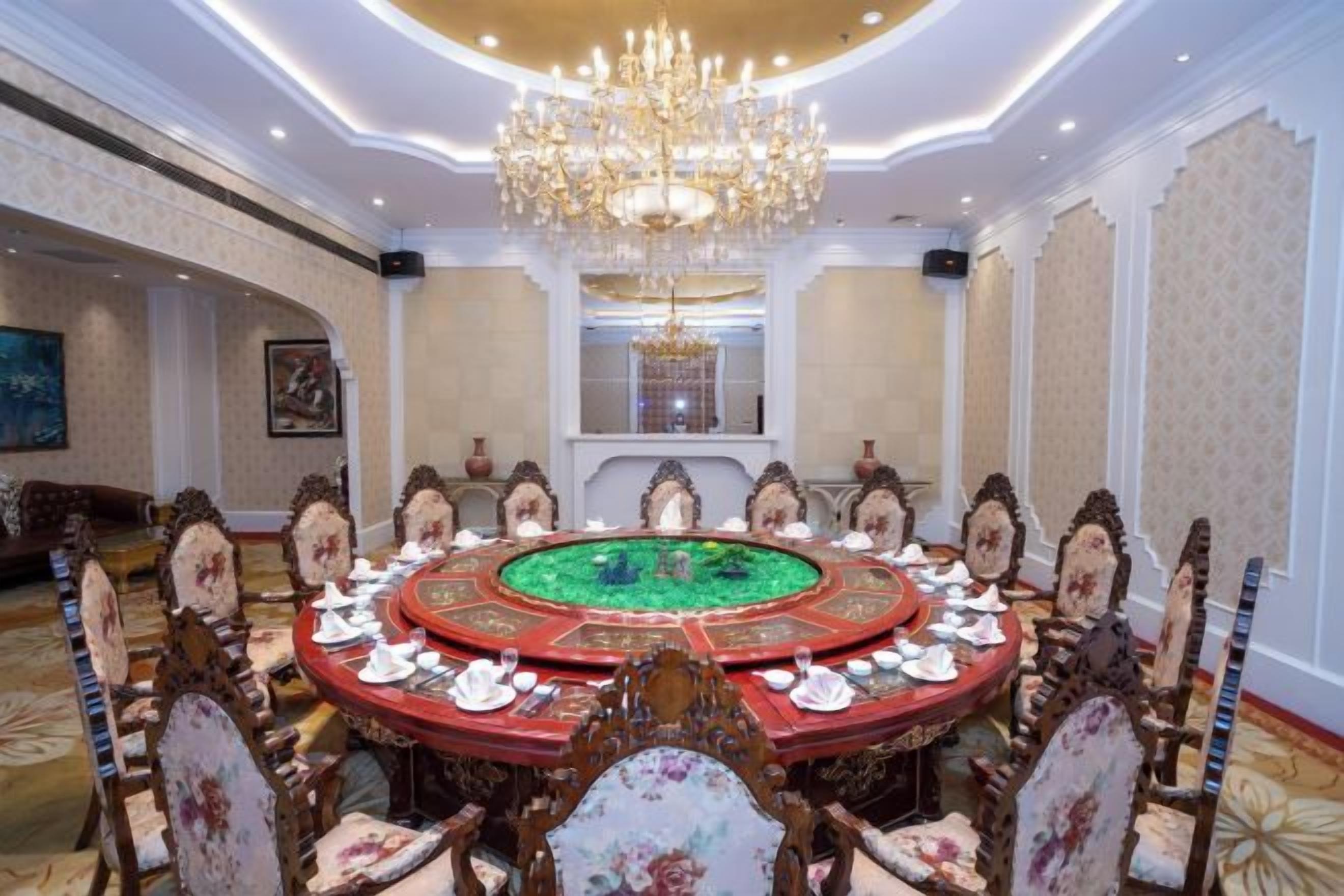 Une salle de réunion formelle, dotée d’une table ronde, de fauteuils élégants et d’un lustre.