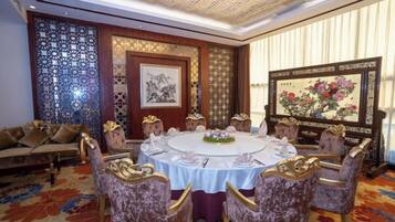 A dining area with a round table, ornate chairs, and traditional artwork.