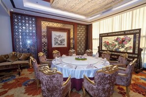 A dining area with a round table, ornate chairs, and traditional artwork. - Taishan Royal Hotel (Tai'an)