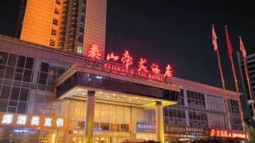 A hotel with a prominent sign, large windows, and a well-lit entrance.