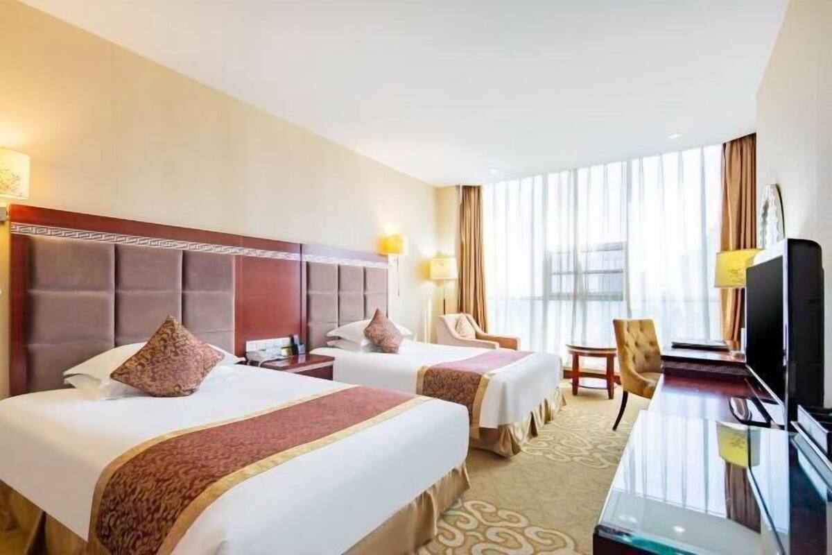 Ein Hotelzimmer mit zwei Betten, einem Schreibtisch, einem Stuhl und einem Fernseher.