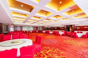 A banquet hall with round tables and red chairs, a patterned carpet, and a ceiling with recessed lighting. - Taishan Royal Hotel (Tai'an)