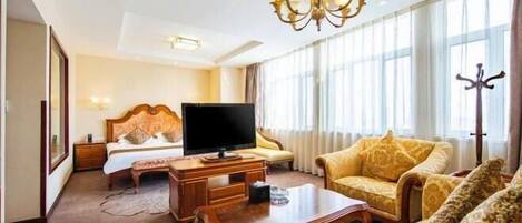 Una habitación de hotel con una cama, un televisor, una mesita de madera y dos sillones estampados.