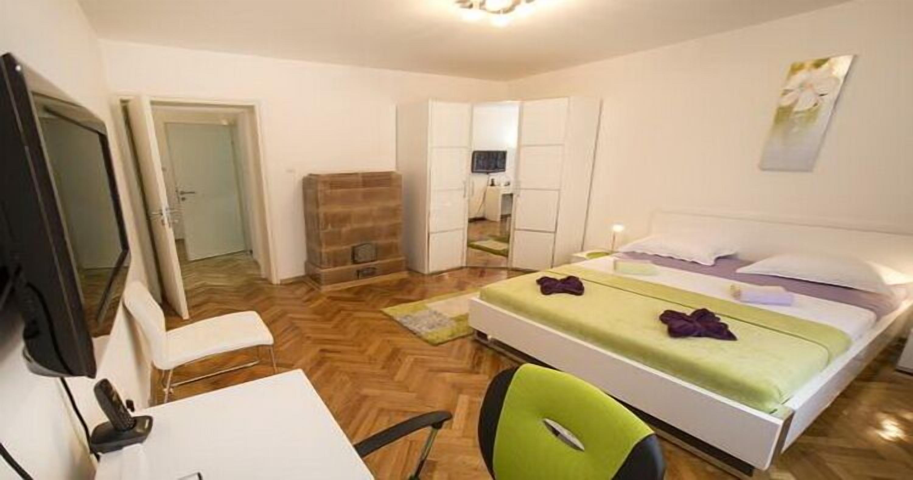 A hotel room with a bed, a desk, a chair, a television, and a wardrobe.
