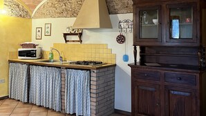 Una cocina con pared de ladrillo, salpicadero de azulejos, mueble de madera y suelo de baldosas.