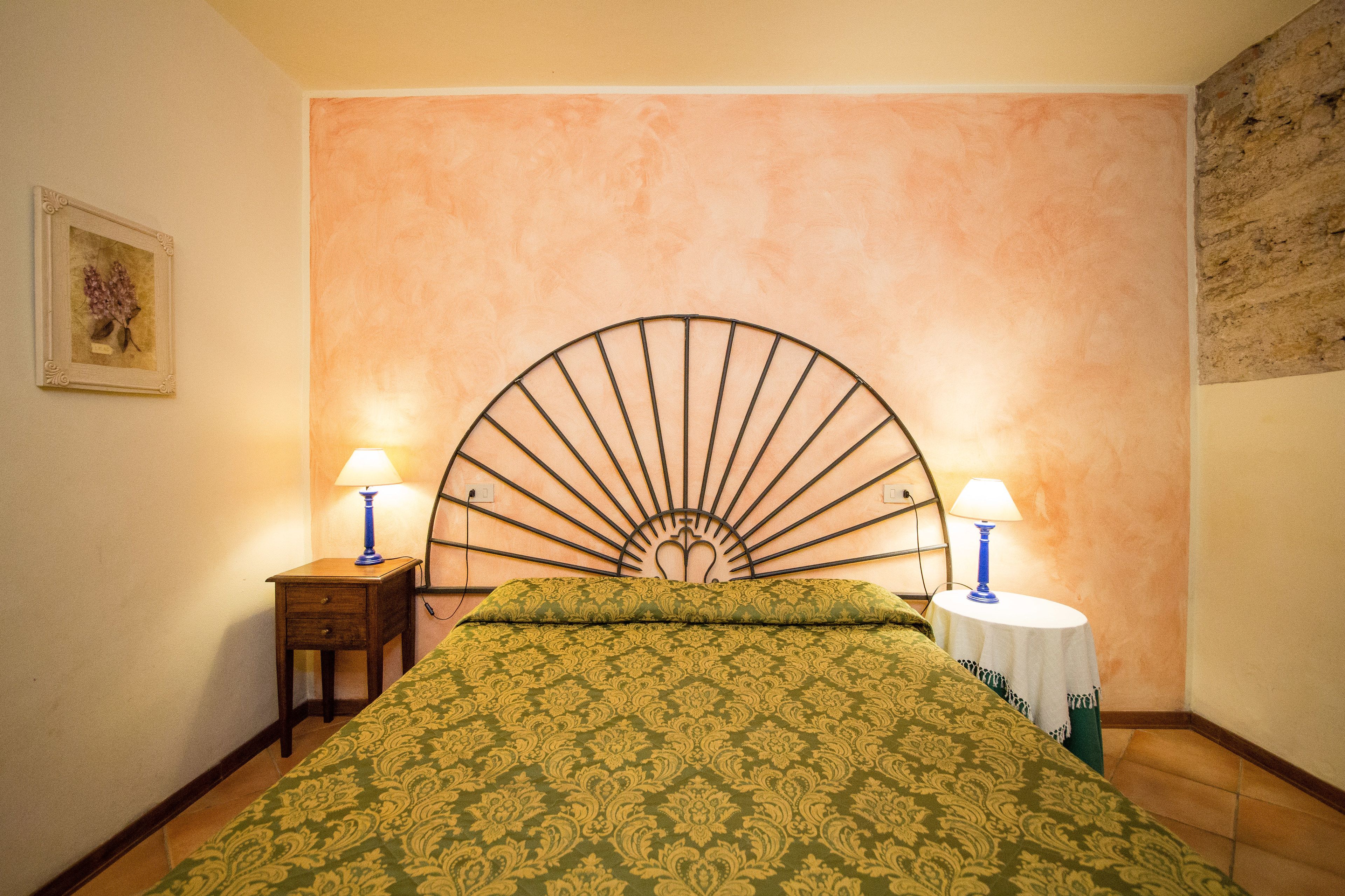 A bedroom with a bed, two bedside tables, and a wall-mounted fan.
