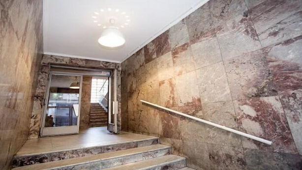 A staircase with marble walls and a handrail, leading to an interior space with a glass door. - Apartment Mozaik (Belgrade)