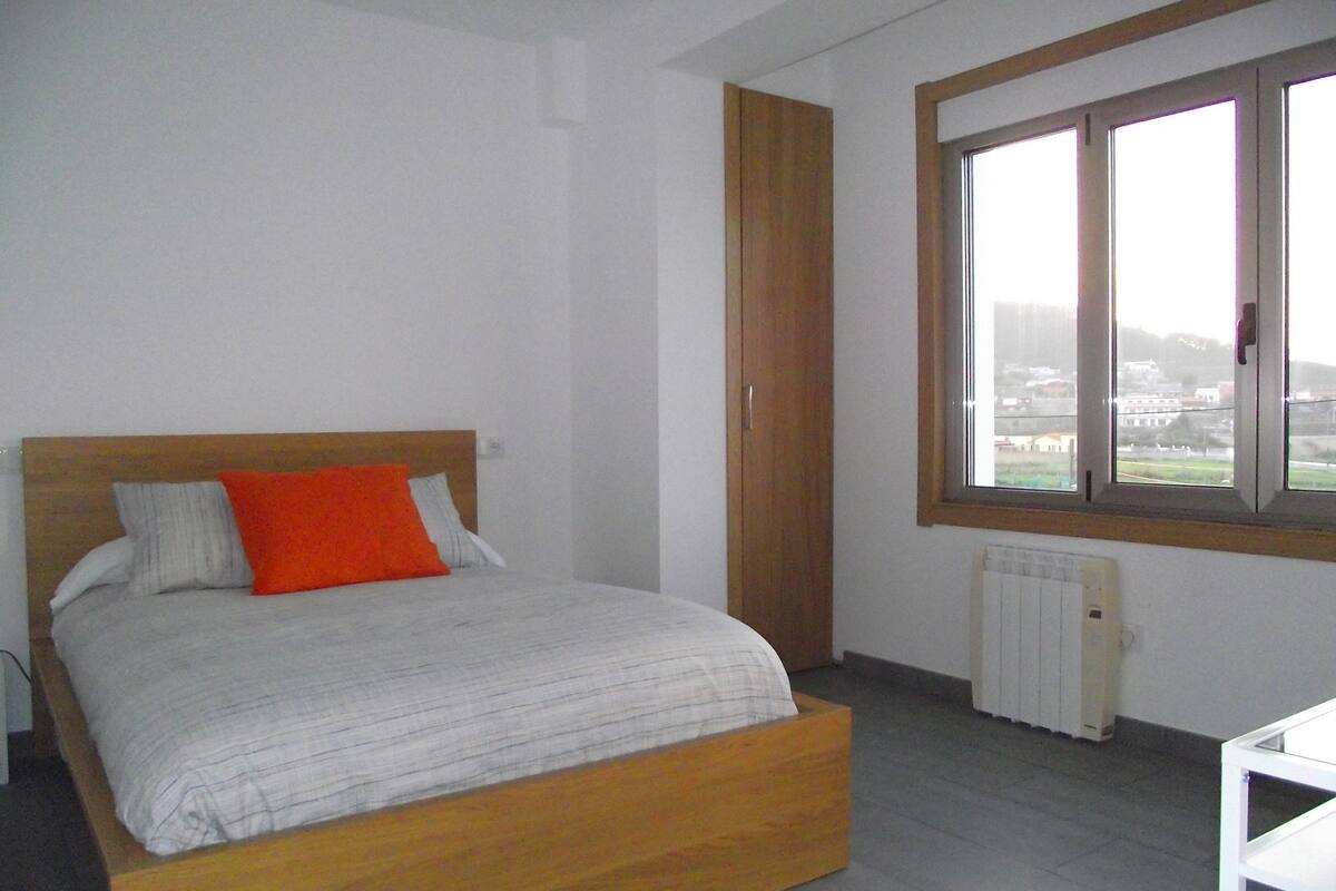 Un dormitorio con una cama de madera, un ventanal y un radiador.