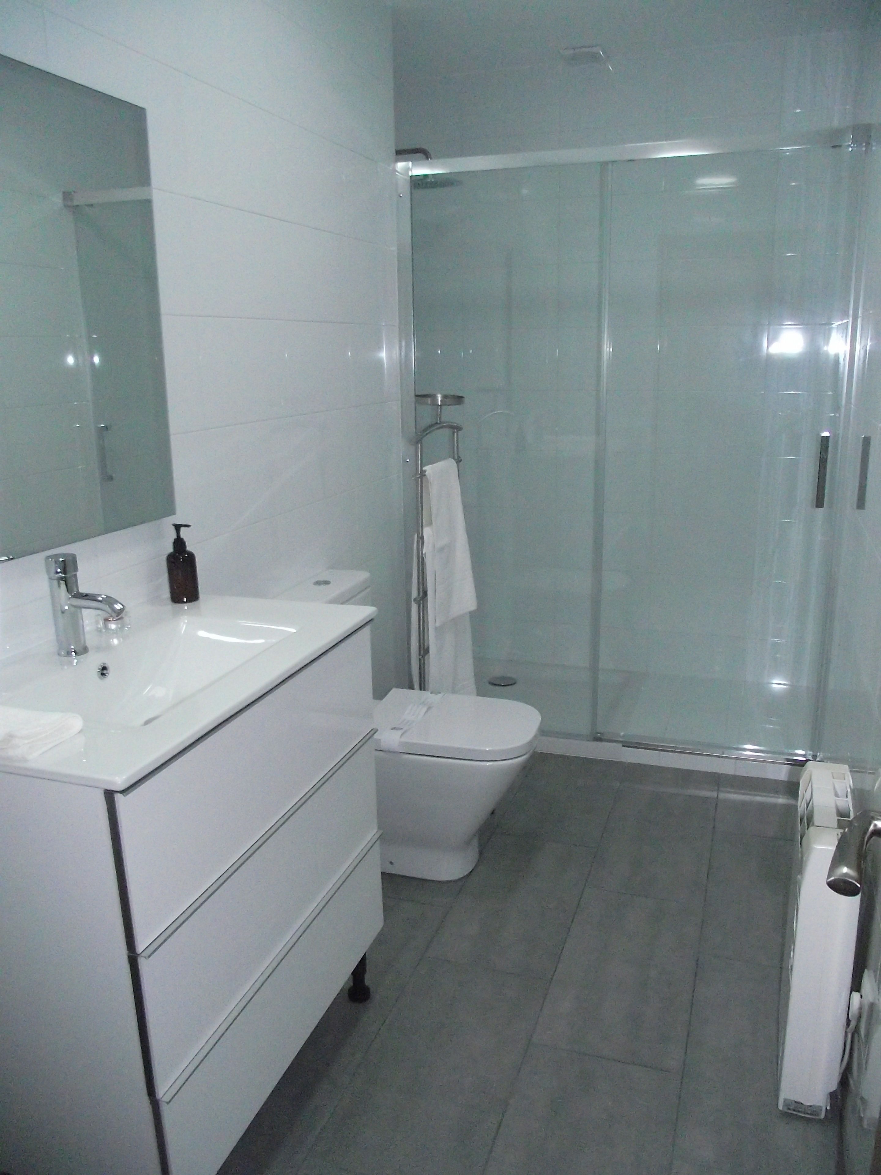 Un baño con lavamanos, espejo y retrete blancos.