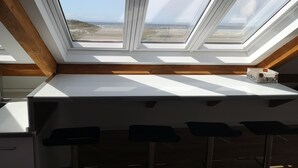 Cocina con tragaluz, vigas de madera y encimera blanca.
